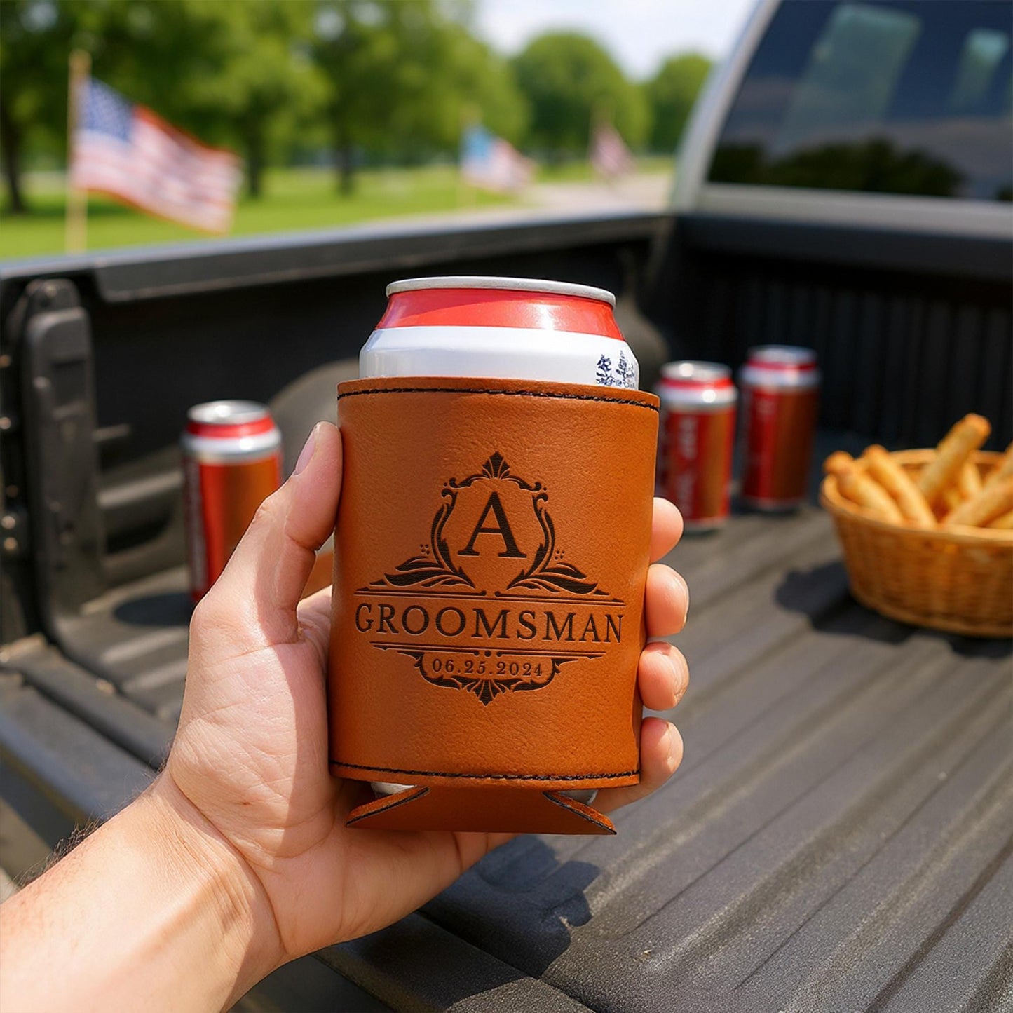 Hand holding personalized leather groomsman can cooler in truck bed with drinks and fries