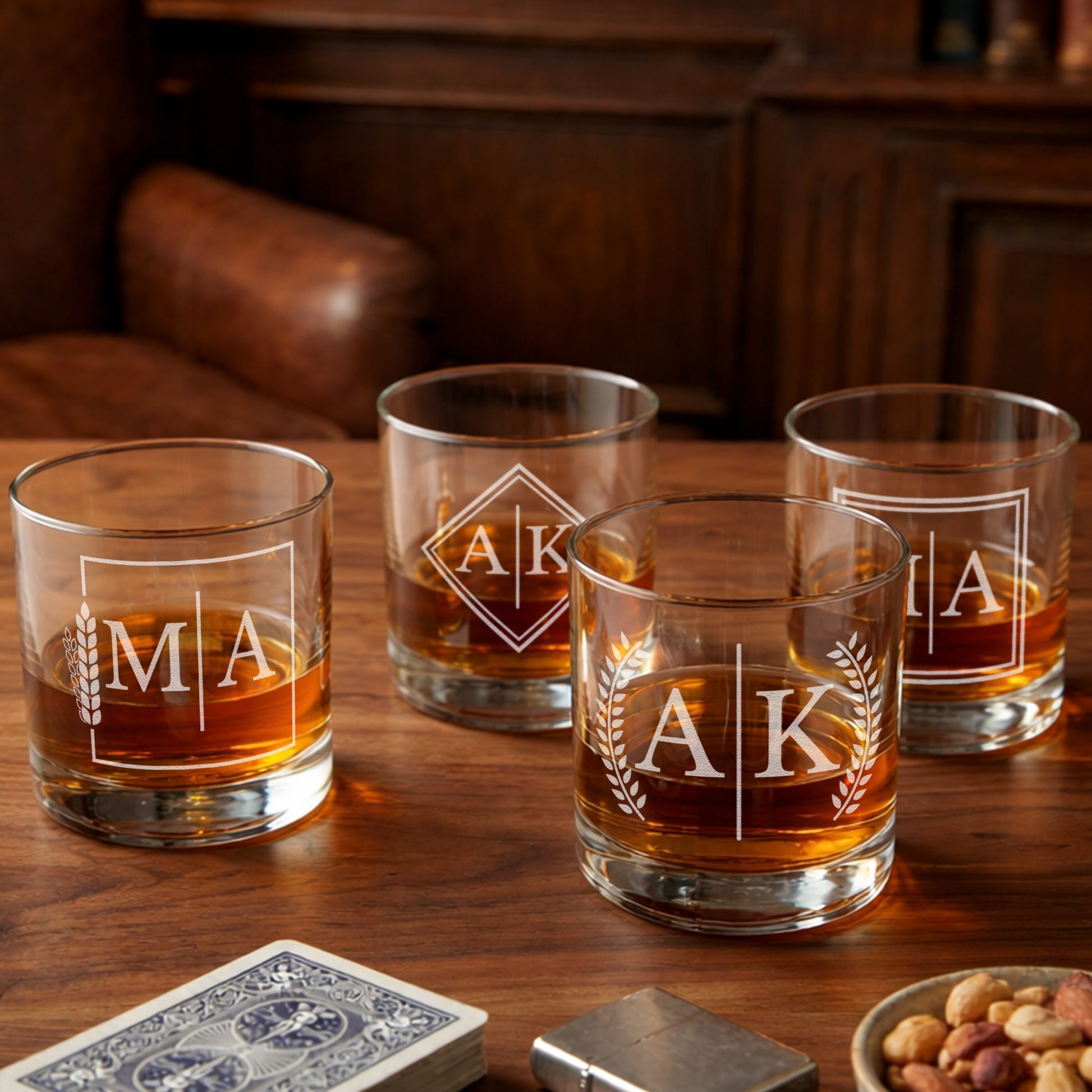 Set of four personalized whiskey glasses with etched initials on wooden table