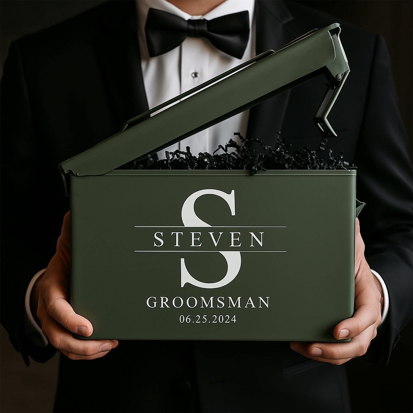 Man in tuxedo holding personalized olive green groomsman gift box with name and date
